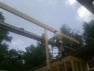 Carpenter setting a ridge beam over a new addition frame — Ice Dam Removal by Roofing Brothers in Hartland