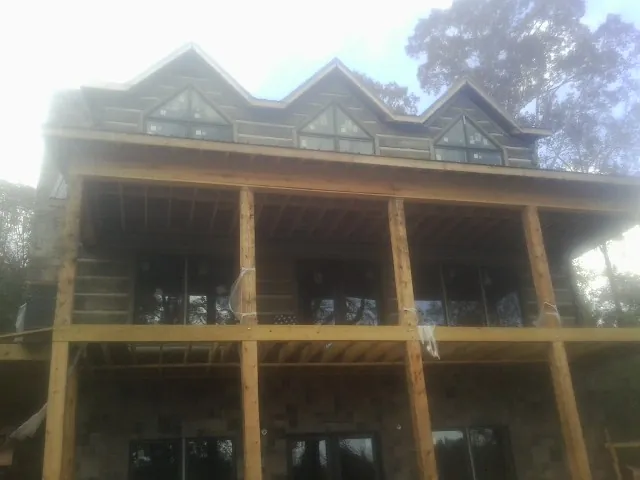Dormers and porch framing on a large log home under construction — Roof Coating work by our crew in Hartland