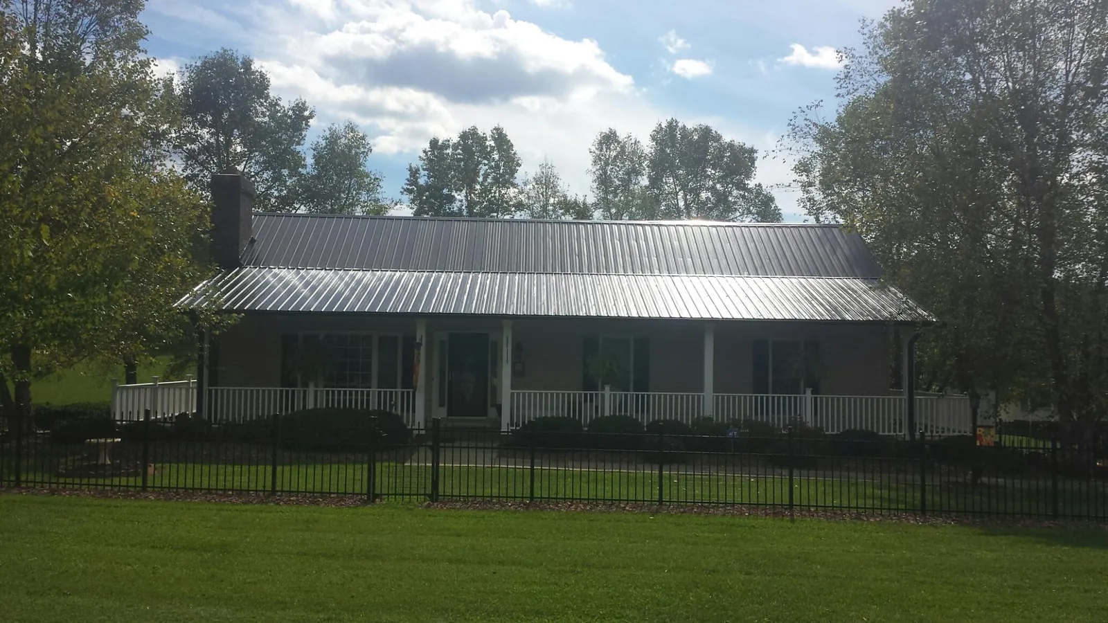 Gray metal roof on a brick ranch with a full width front porch in Hartland